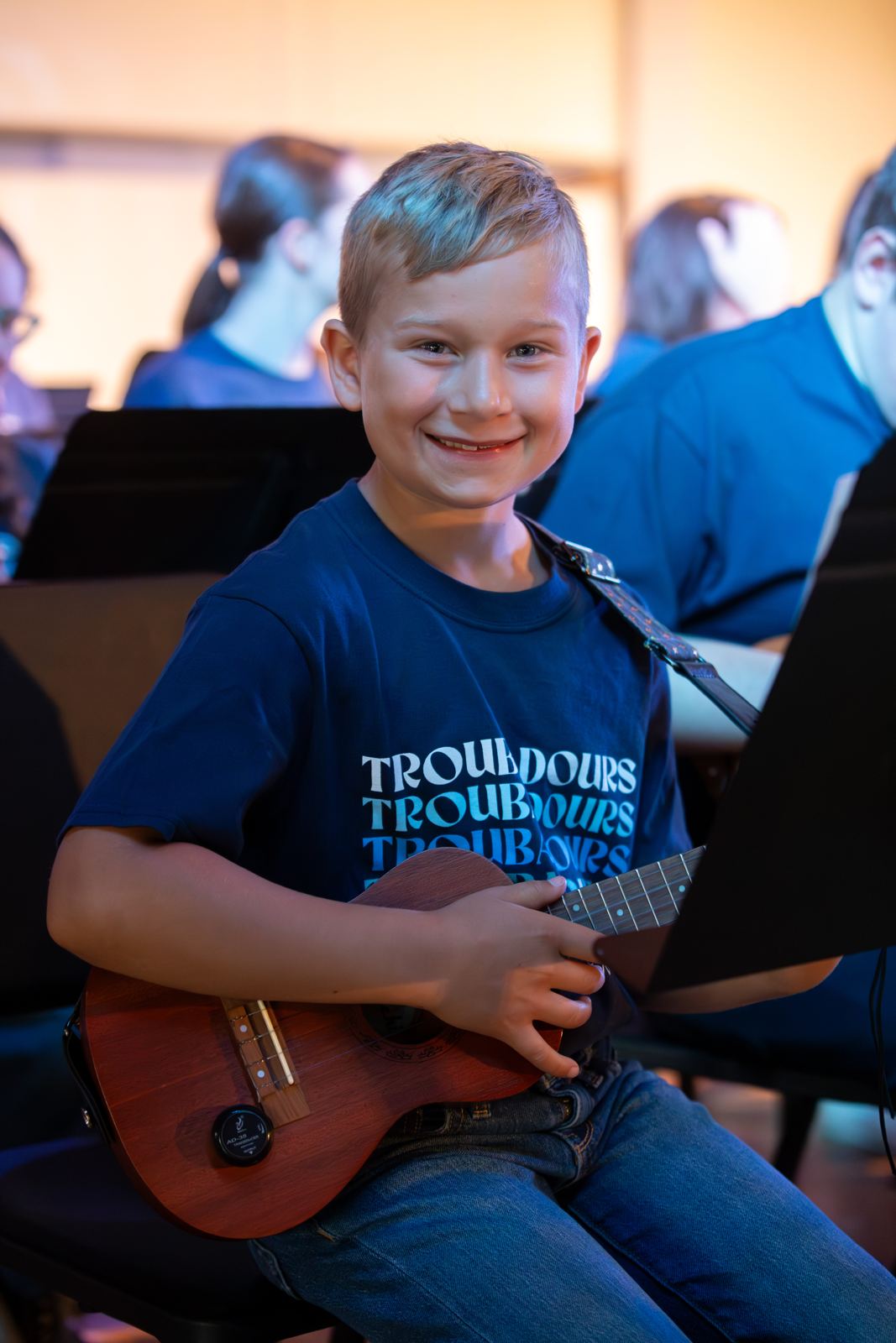 Smiling young student playing ukulele